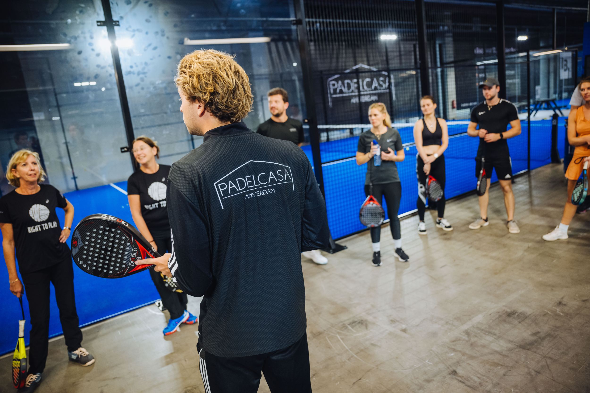 Trainer geeft uitleg aan een groep deelnemers op de baan