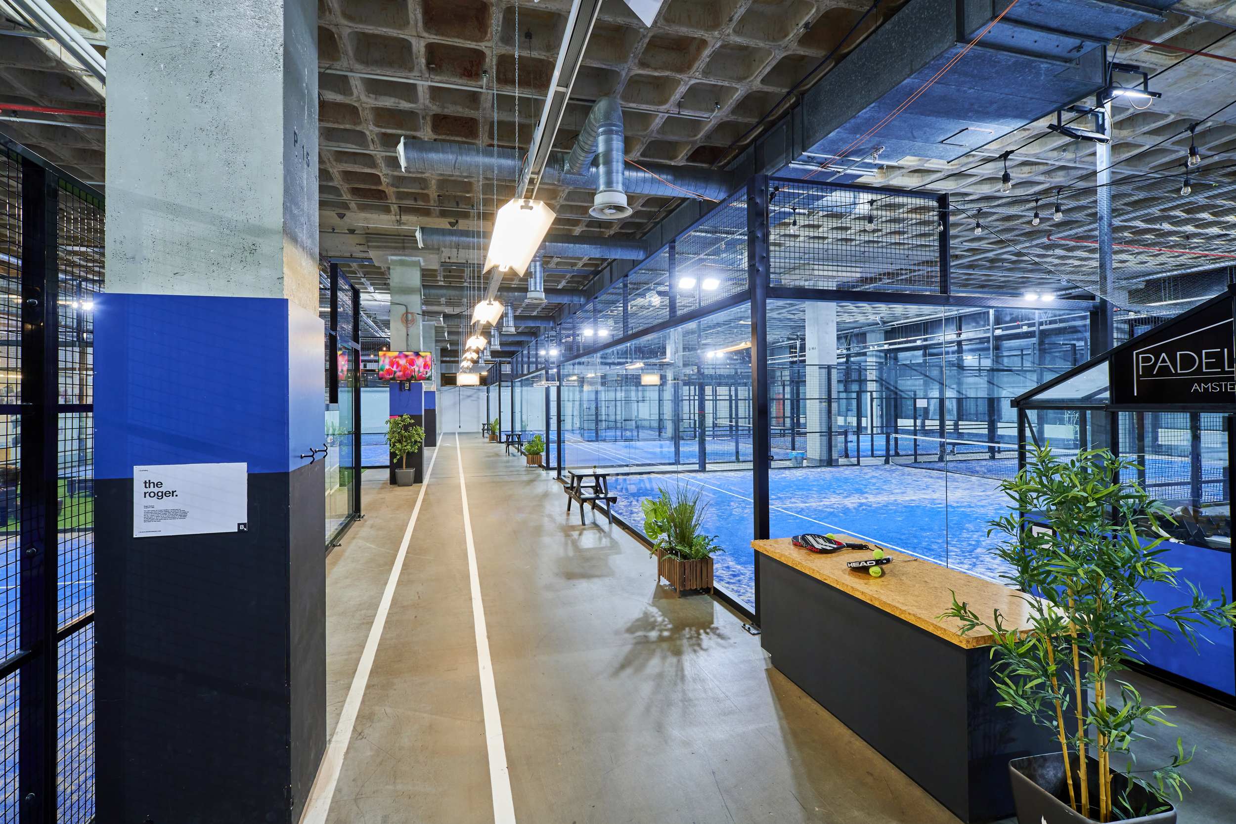 Overzicht van de padelhal in B.1 met het middenpad tussen de banen